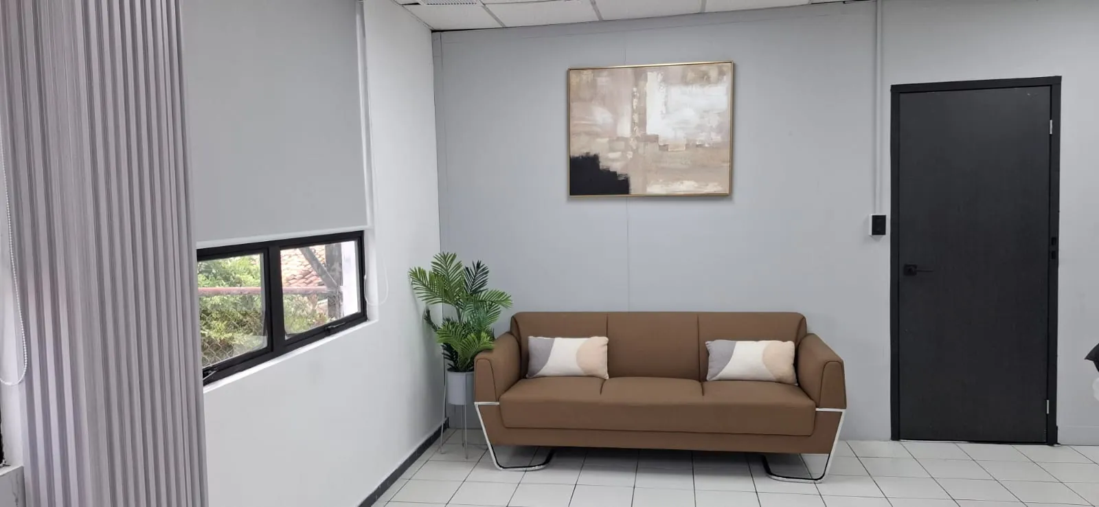 Sala de espera con sofá tapizado de tres plazas sobre base metálica