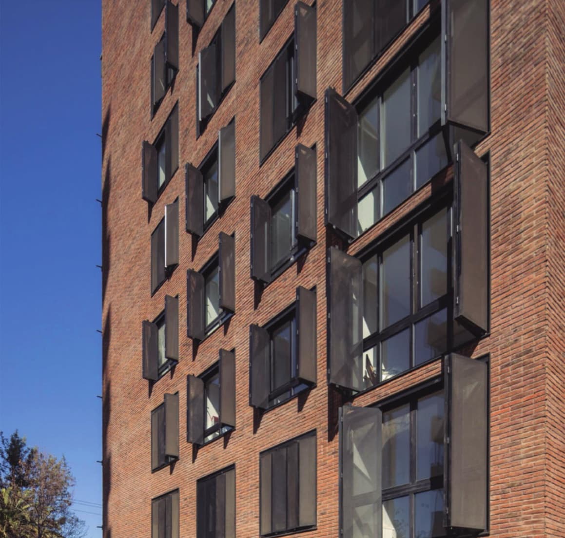 Brick building with folding metal shutters open in front of the windows