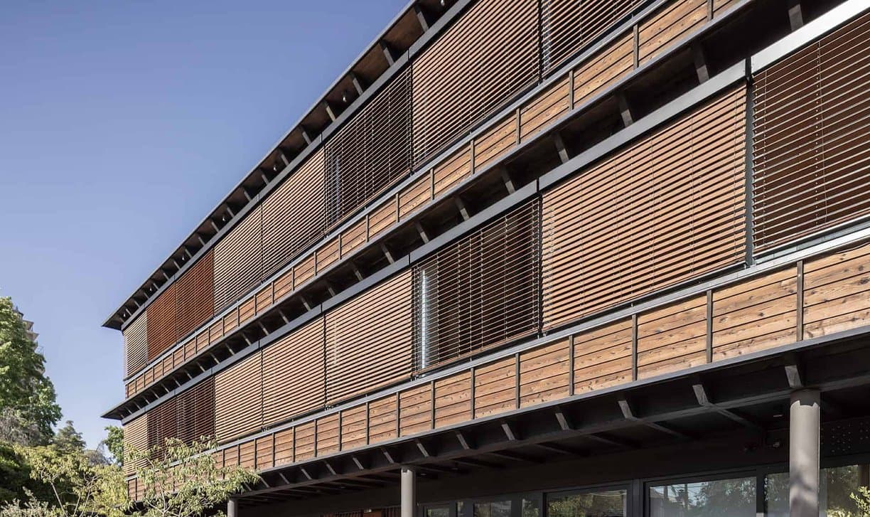 Multi-storey façade with wooden-slat exterior blinds, some open and some closed