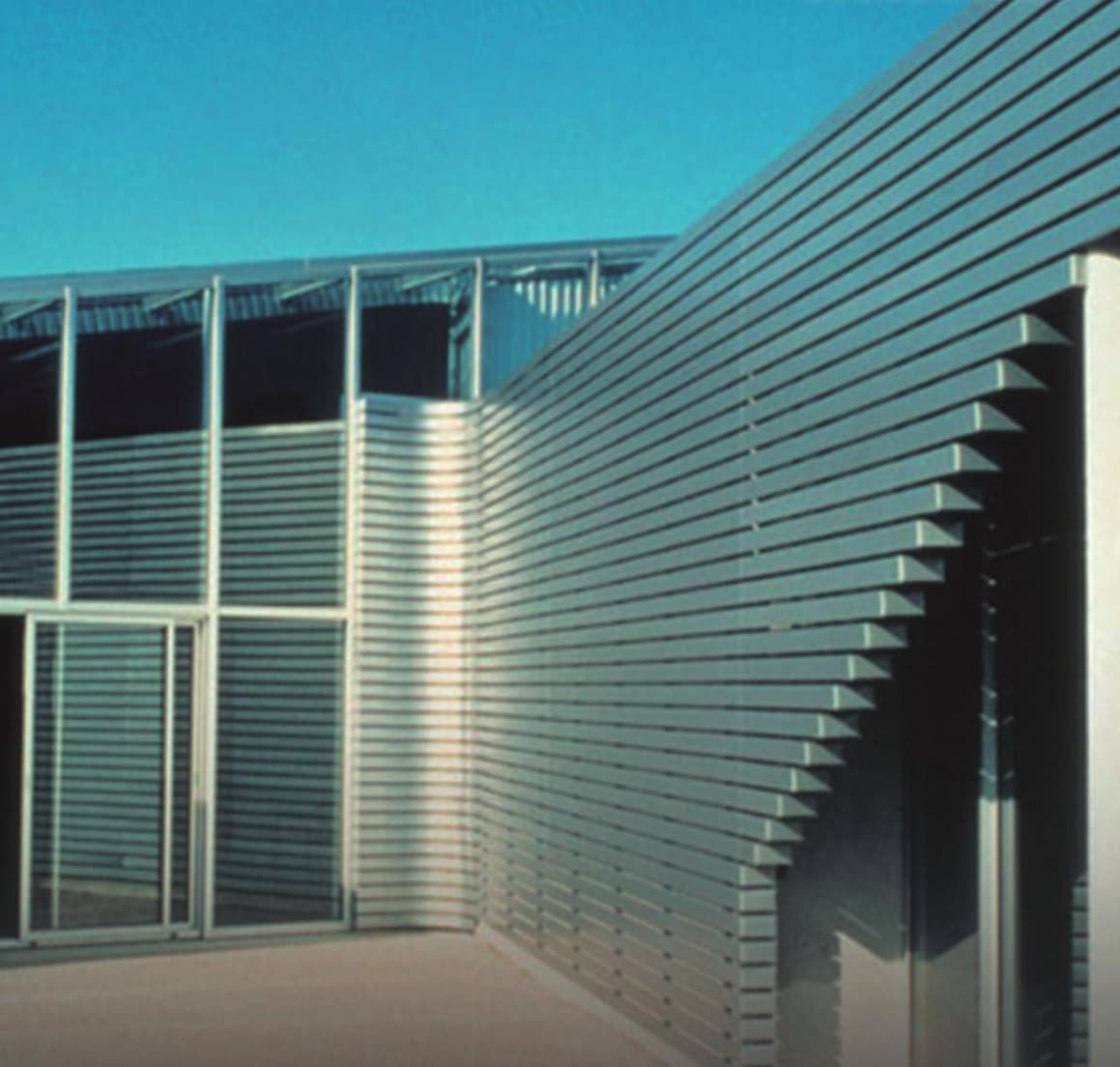 Façade clad in 84R linear metal panels with curved edges