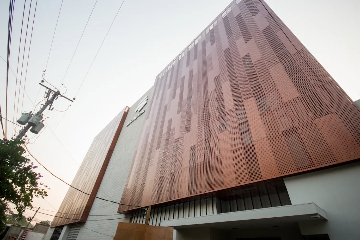 Edificio ALPHA clad in copper-colour perforated panels seen from below